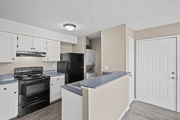 A kitchen with black appliances and white cabinets.