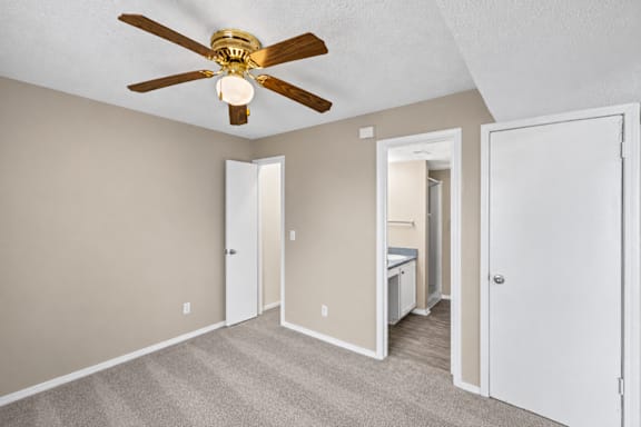 A room with a ceiling fan and carpeted floor.