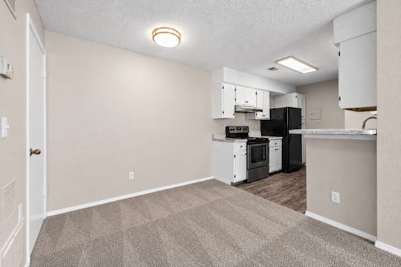A kitchen with white appliances and a black refrigerator.