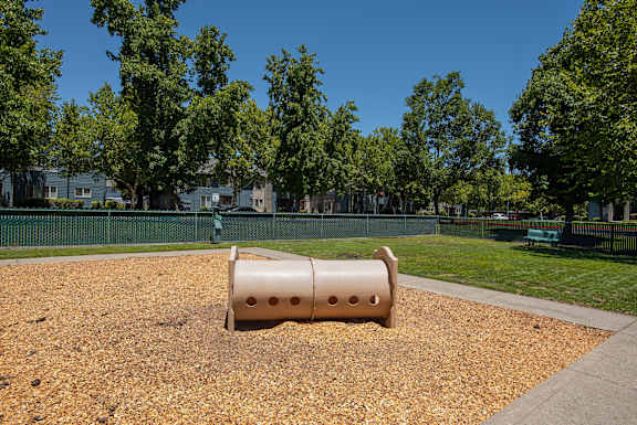 A dog park with a beige cylinder and bark dust at Autumn Oaks Apartments, Roseville, CA, 95678