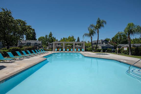A large swimming pool with lounge chairs and a fountain in the middle at Autumn Oaks Apartments, Roseville, CA