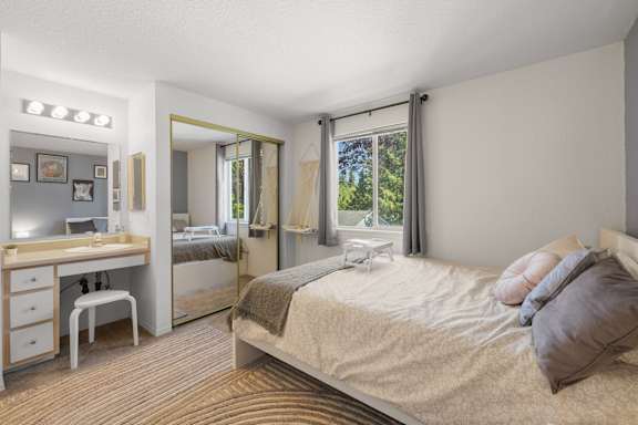 A bedroom with a bed, vanity, and chair at Clackamas Trails Apartments, Oregon, 97222