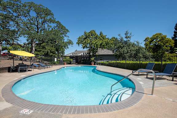 A round swimming pool surrounded by trees and chairs at Rocklin Gold Apartments, California, 95677