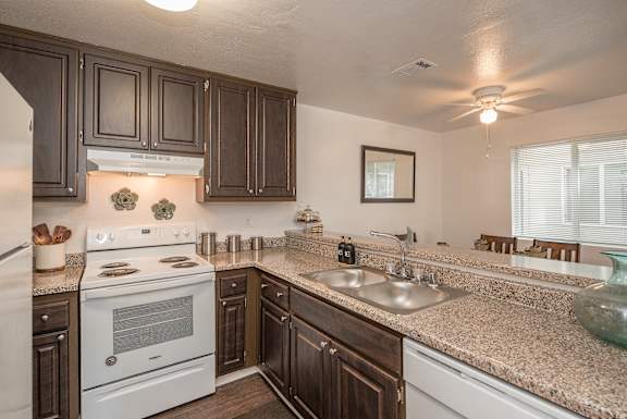 A kitchen with a white stove and brown cabinets at Sierra Glen Apartments, California, 95621