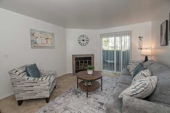 A living room with a grey couch, a wooden coffee table, and a painting on the wall at Sierra Glen Apartments, California, 95621