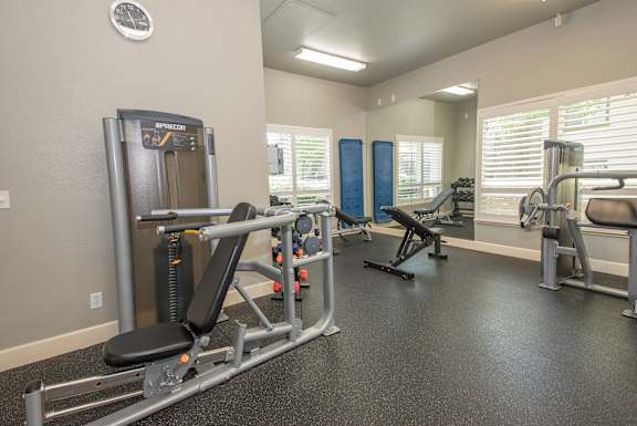 A gym with a variety of equipment including a leg press machine at Stoneridge Apartments, California, 95661