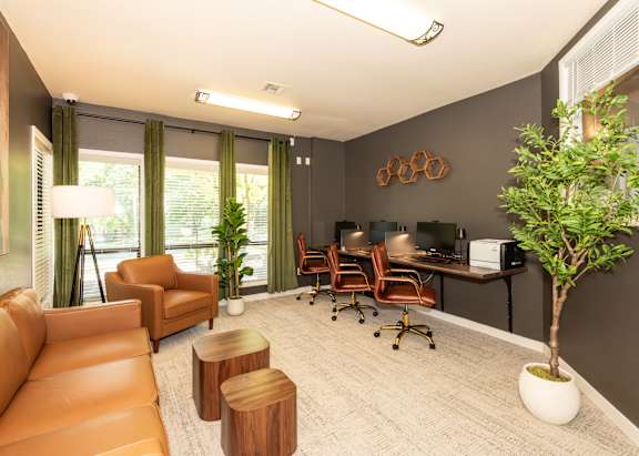 A room with a brown couch, a desk with chairs, and a potted plant at Sunstone Parc, Beaverton, OR, 97008