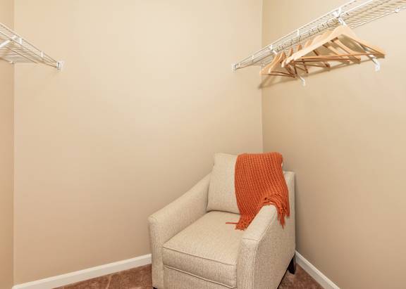 A white chair with an orange blanket draped over it in a large closet at The Landing Apartments and Townhomes, Oregon, 97045