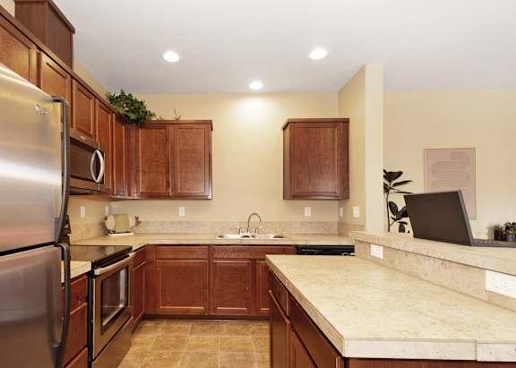 A kitchen with wooden cabinets and a tan countertop at The Landing Apartments and Townhomes, Oregon, 97045