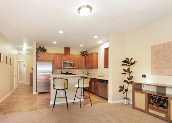 A kitchen with a refrigerator, microwave, and a dining bar with two chairs at The Landing Apartments and Townhomes, Oregon, 97045