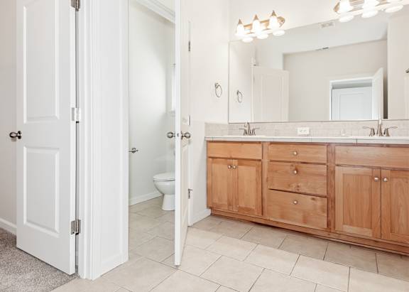 A bathroom with a white door and a wooden cabinet at The Landing Apartments and Townhomes, Oregon, 97045