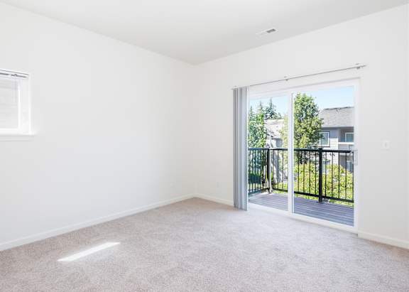 A room with a carpeted floor and a sliding glass door leading to a balcony at The Landing Apartments and Townhomes, Oregon, 97045
