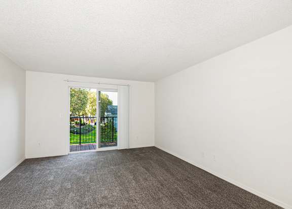 A room with a grey carpet and white walls with a sliding glass door at Todd Village Apartments, Oregon, 97062