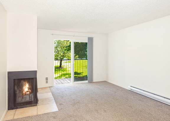 A room with a fireplace and sliding glass doors leading to grass at Todd Village Apartments, Oregon, 97062