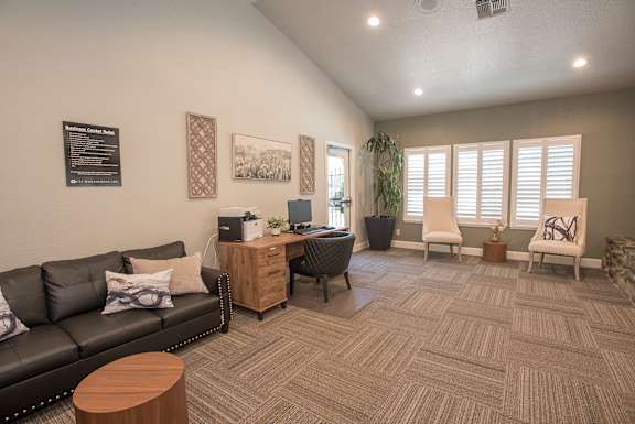 A business center with a black couch, a wooden coffee table, and a carpet on the floor at Zinfandel Village Apartments, California, 95670