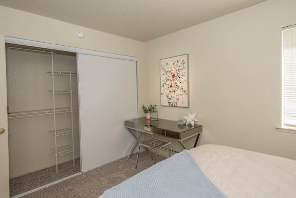 A bedroom with a bed, desk, chair, and a painting on the wall at Zinfandel Village Apartments, California, 95670