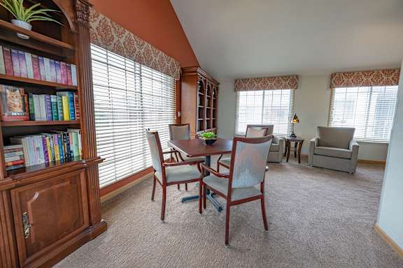 A room with a table, chairs, and a bookshelf.