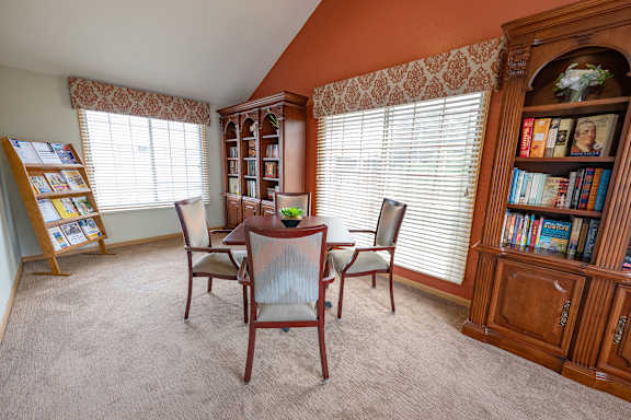 A room with a table, chairs, and bookshelves.
