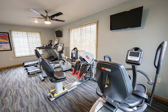 A home gym with a variety of equipment including treadmills, stationary bikes, and weight machines.