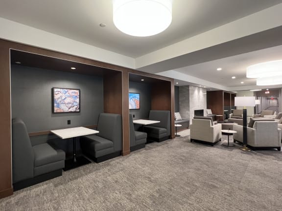 a lounge area with chairs and tables in a room
