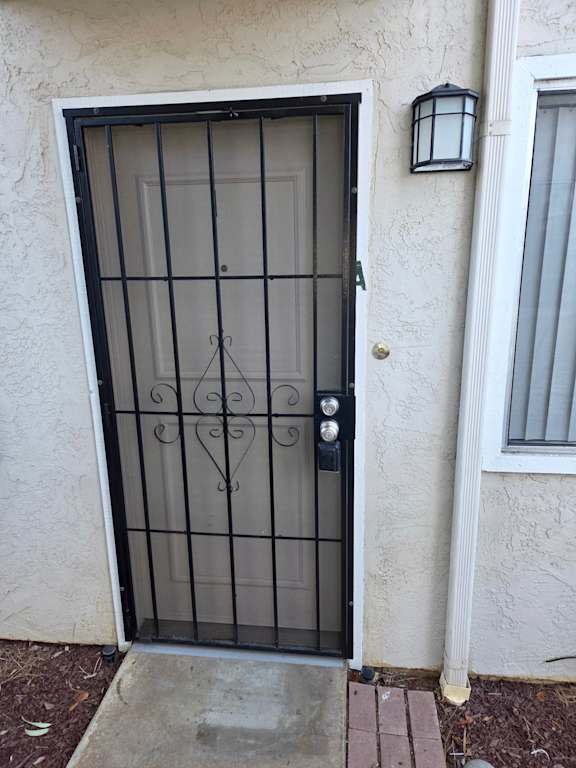 A black metal gate with a decorative design is on a white wall.