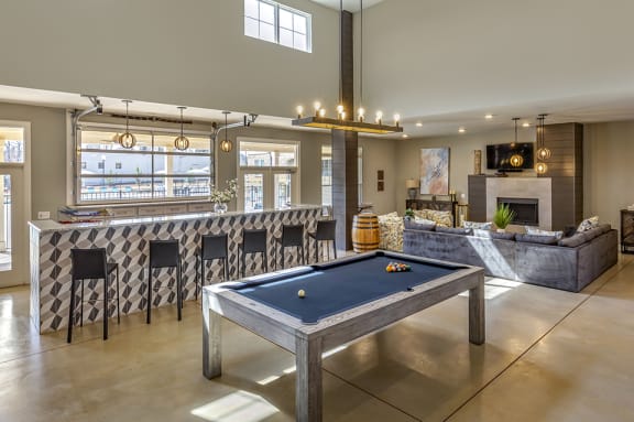 a pool table in a living room with a bar and a fireplace