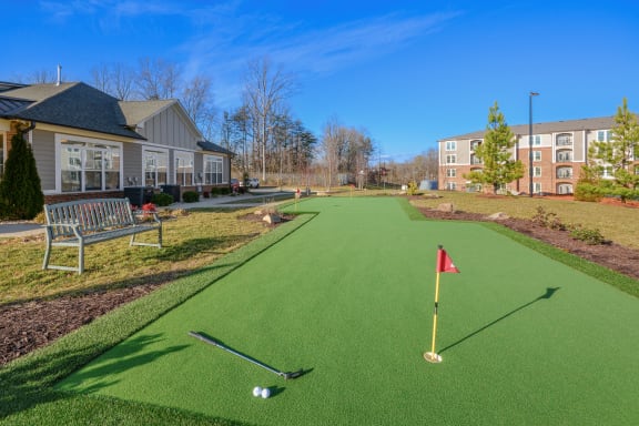 a putting green in front of a house with a golf ball on it