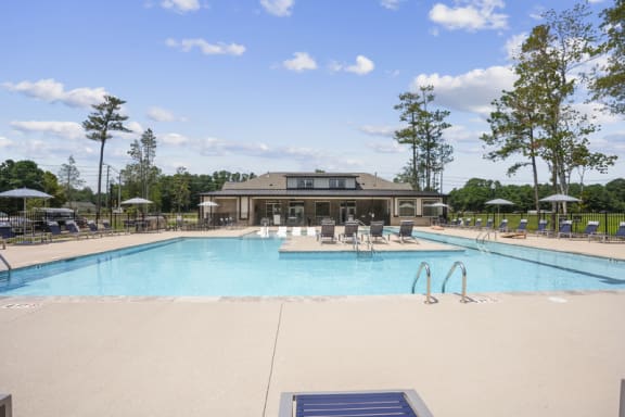 a swimming pool with chairs and a building in the background