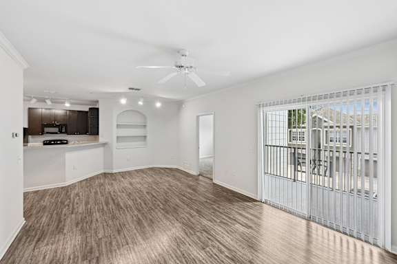 A spacious living room with a ceiling fan and a view of a balcony.