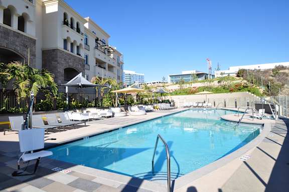 Resort style pool with lounge chairs and umbrellas at 360 Luxury Apartments, San Diego, California