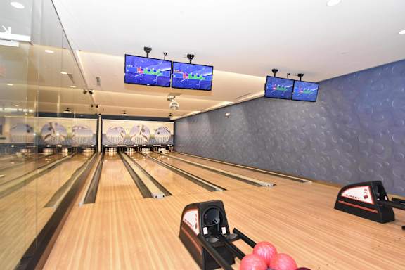 A bowling alley with a row of lanes and bowling balls.