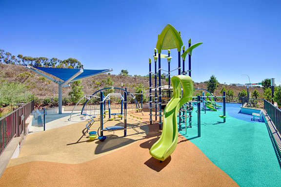 A playground with a yellow slide and a blue shade structure.