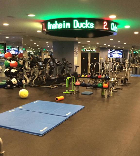 Fitness center with cardio equipment and scoreboard display at Torrey Gardens Apartments, San Diego, California