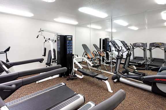 A gym with a variety of equipment including treadmills, weights, and exercise machines.