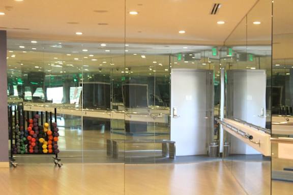 Fitness studio with mirrored walls and barre rail at Torrey Gardens Apartments, San Diego