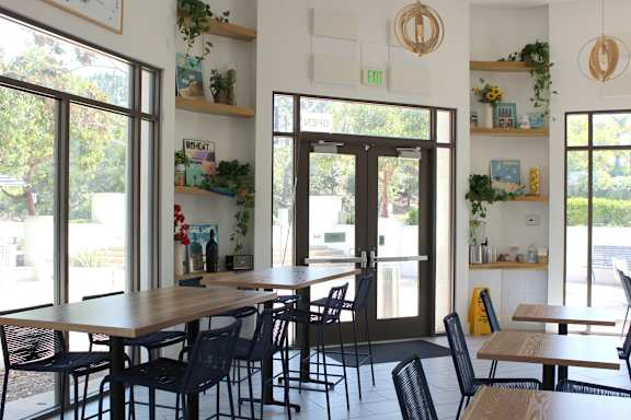 Bright cafe dining area with wooden tables and shelving at Torrey Gardens Apartments, San Diego, CA 92130