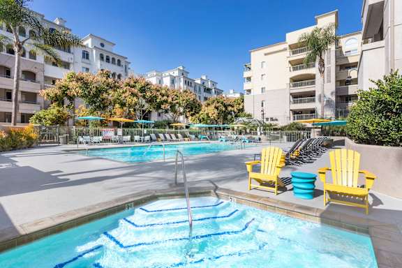 A pool with blue water and yellow chairs.