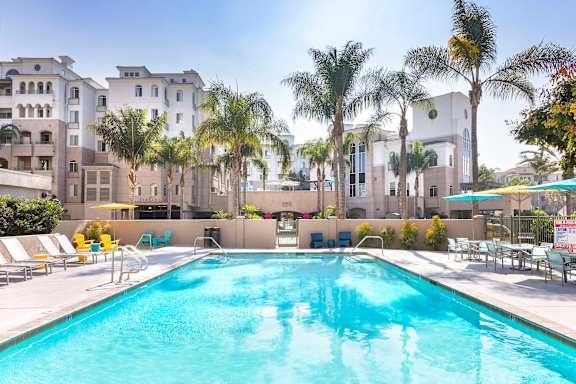 A large swimming pool in front of a building with palm trees.