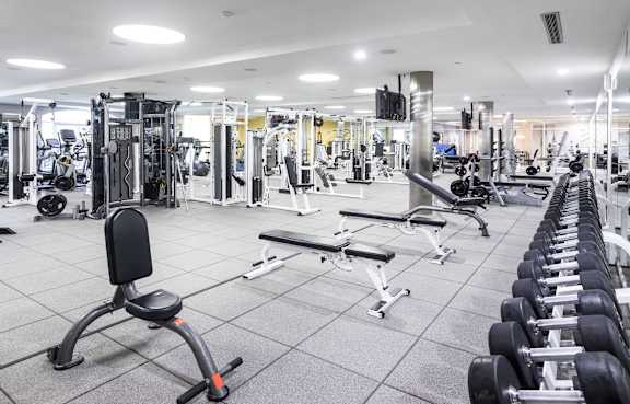 A spacious gym with a variety of equipment including treadmills, weight machines, and dumbbells.