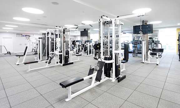 A gym with a variety of equipment including a squat rack, bench, and weights.