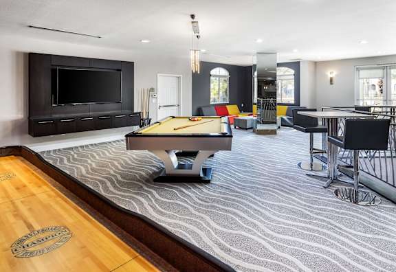 A billiard table is in the middle of a room with a television and a pool table.