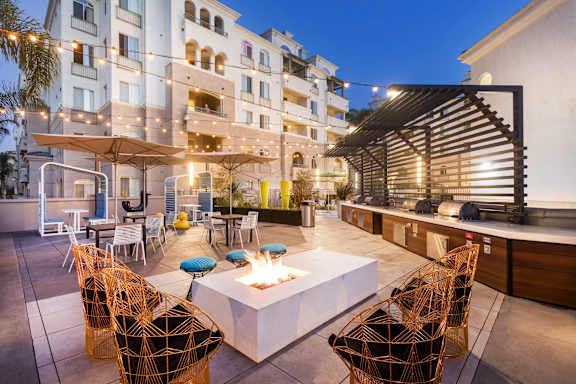 A patio with a fire pit surrounded by chairs.