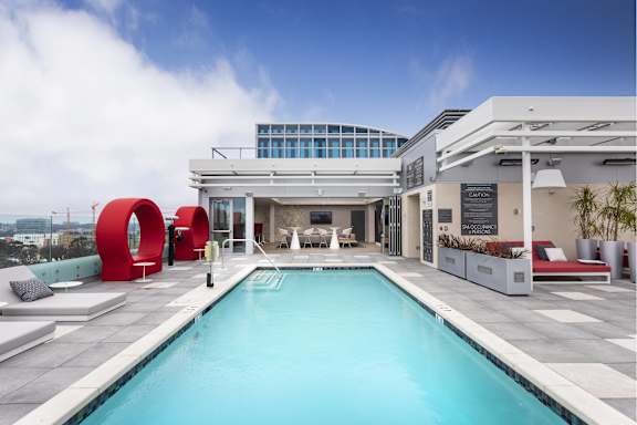 Rooftop pool deck with lounge seating area at LUX by Garden* Apartments, San Diego, CA