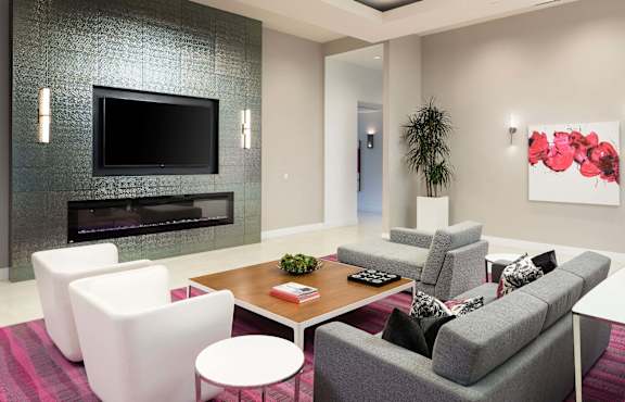 Community lounge with fireplace and wall mounted television at Metropolis Apartments, IRVINE, CA 92614