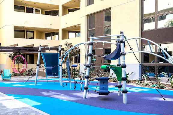 Playground with climbing structure and colorful safety surfacing at Metropolis Apartments, IRVINE, CA