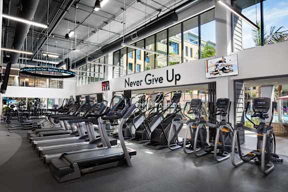 Fitness center with cardio equipment and motivational signage at Metropolis Apartments, IRVINE, 92614