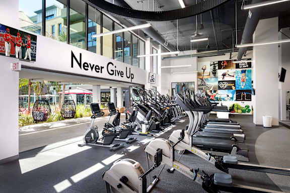 Fitness center with cardio equipment and motivational wall art at Metropolis Apartments, IRVINE, California