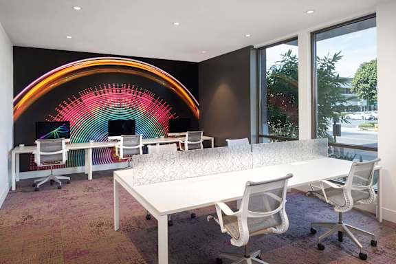Modern workspace with colorful rainbow wall mural at Metropolis Apartments, IRVINE