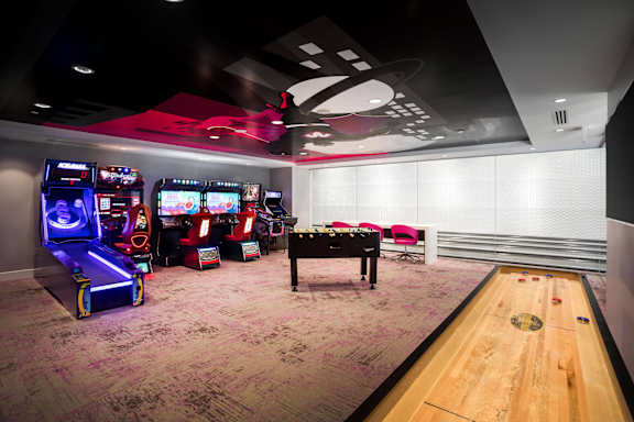 Game room with arcade machines and shuffleboard table at Metropolis Apartments, California