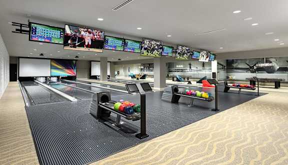 Private bowling lanes with colorful balls and overhead screens at Elements Apartments, Irvine
